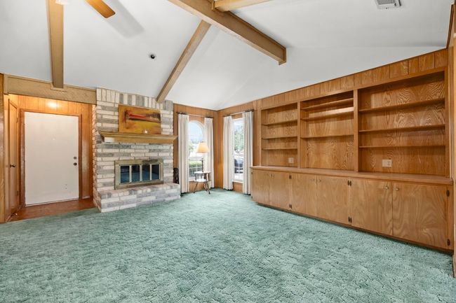 Unfurnished living room with a fireplace, carpet, a ceiling fan, and wooden walls | Image 6