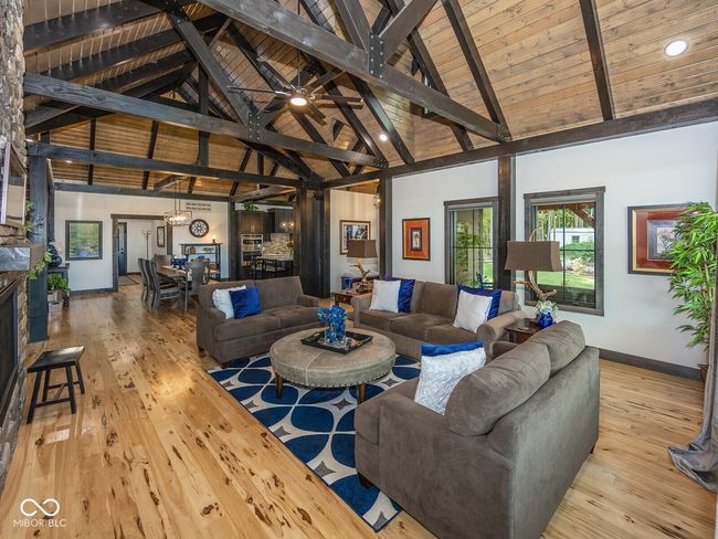 living area with hardwood / wood-style flooring, high vaulted ceiling, baseboards, wood ceiling with exposed beams, and a fireplace | Image 9