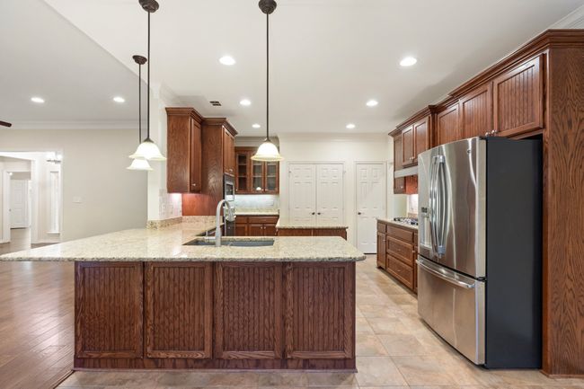 Kitchen featuring appliances with stainless steel finishes, a sink, ornamental molding, a peninsula, and recessed lighting | Image 7