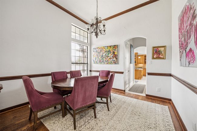 Dining area with wood finished floors, arched walkways, a chandelier, crown molding, and a towering ceiling | Image 12
