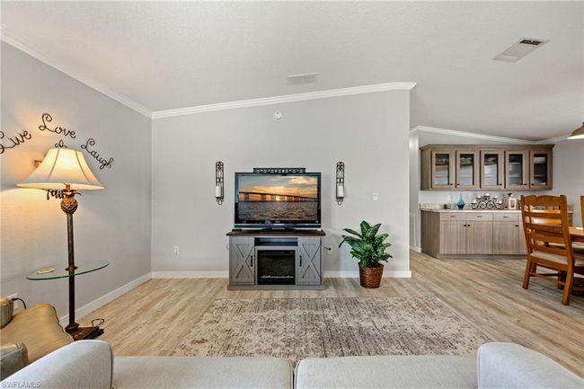 Living room with visible vents, light wood-type flooring, crown molding, and baseboards | Image 17