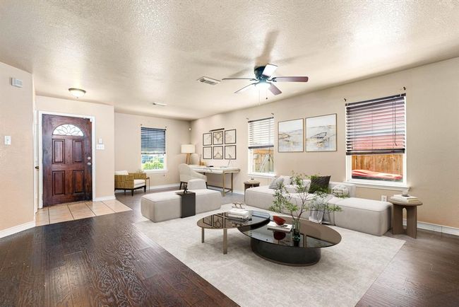 This light and bright spacious living room is the perfect layout for entertaining or just relaxing. Whether it's simply a night in or entertaining family and friends, this home has ample open space for everyone to enjoy! Featuring dark stained ceiling fan, large wood style flooring, large windows with blinds, high ceilings, and easy access to your dining room and kitchen. *Virtually Staged | Image 5