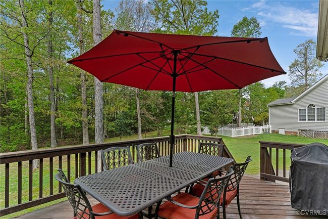 Wooden deck featuring a lawn, outdoor dining space, grilling area, and a fenced backyard | Image 46