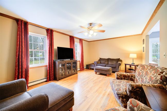 Living room featuring a baseboard radiator, light wood-style flooring, ornamental molding, and ceiling fan | Image 6