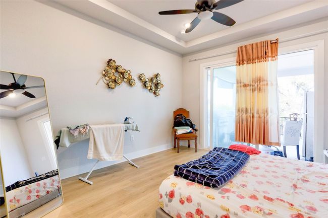 Bedroom with a tray ceiling, access to exterior, a ceiling fan, light wood-style flooring, and baseboards | Image 22