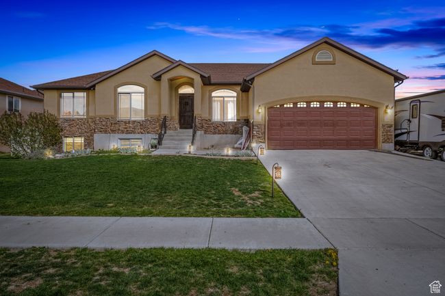 Ranch-style home with stucco siding, stone siding, a front lawn, concrete driveway, and an attached garage | Image 42