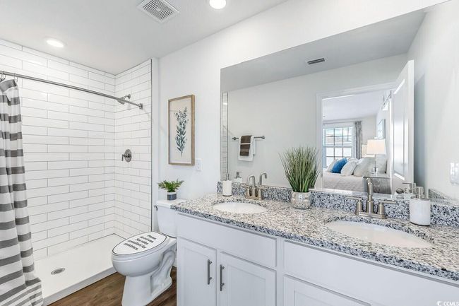 Ensuite bathroom with double vanity, a tile shower, and wood finished floors | Image 18