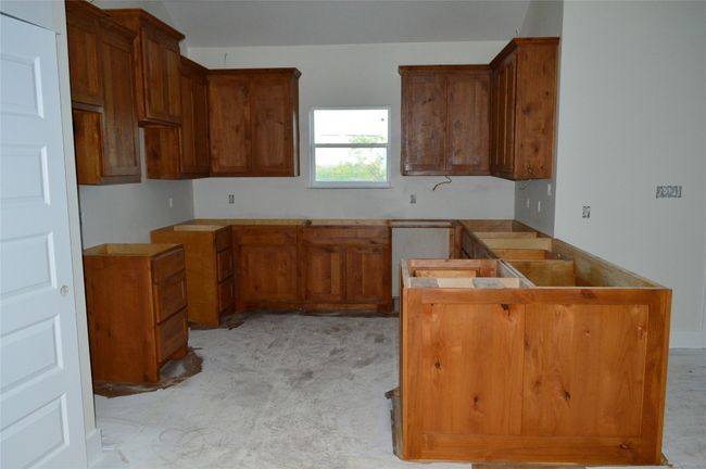 Kitchen with brown cabinets, a peninsula, and light carpet | Image 11