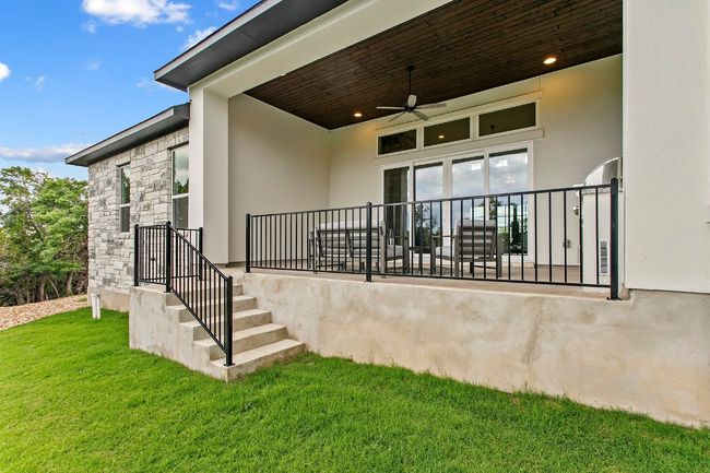 Doorway to property with a lawn, stucco siding, ceiling fan, and stone siding | Image 40