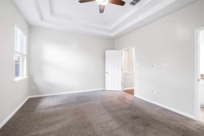 Unfurnished room with a tray ceiling, a ceiling fan, and carpet flooring | Image 23