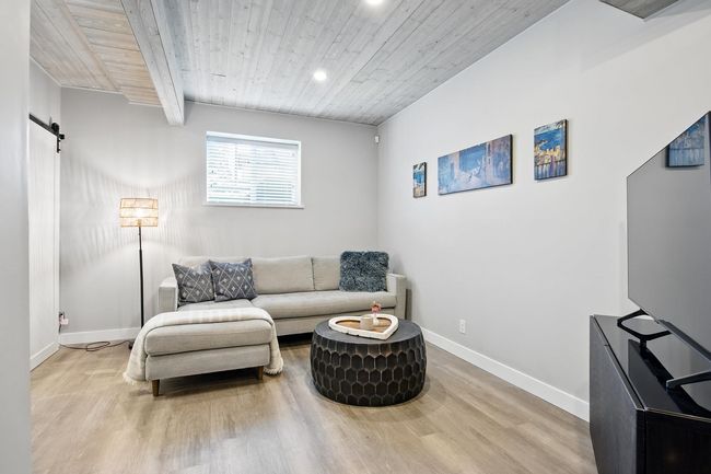 Living area with wood finished floors, baseboards, recessed lighting, wood ceiling, and a barn door | Image 25