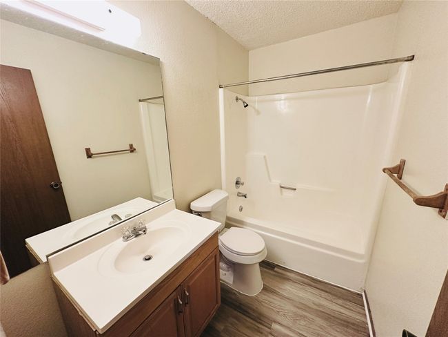 Bathroom with a textured ceiling, wood finished floors, vanity, and bathing tub / shower combination | Image 23