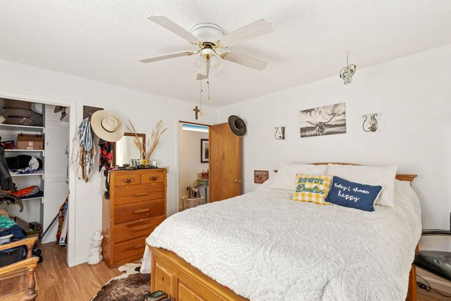 Separate apartment - Bedroom with light wood-type flooring, a spacious closet, a textured ceiling, a ceiling fan, and a closet | Image 78