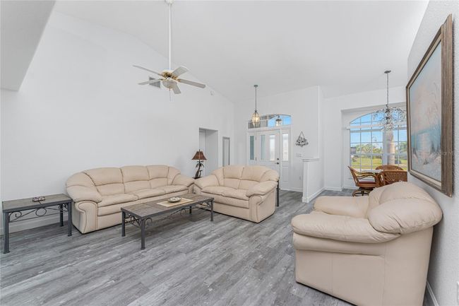 Living room has a cathedral ceiling and ceiling fan | Image 4