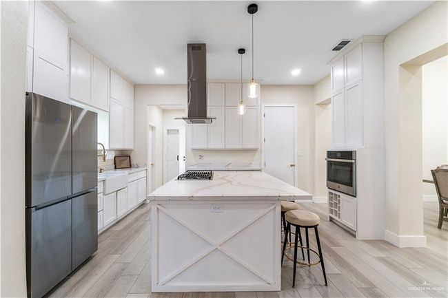 Kitchen with range hood, a center island, light wood-type flooring, stainless steel appliances, and pendant lighting | Image 23
