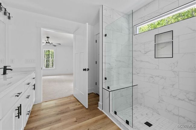 Full bath with double vanity, a marble finish shower, wood finished floors, a ceiling fan, and a sink | Image 20