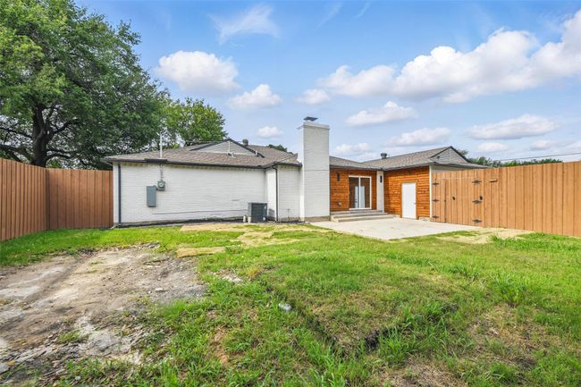 Rear view of house featuring a chimney, a patio, a gate, and cooling unit | Image 37