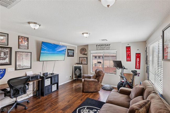 Living room with dark wood-type flooring, a textured ceiling, baseboards, and a desk | Image 15