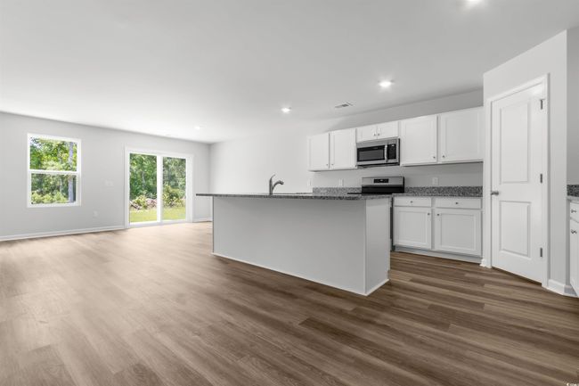 Kitchen featuring appliances with stainless steel finishes, white cabinets, a center island with sink, and dark hardwood / wood-style flooring | Image 13