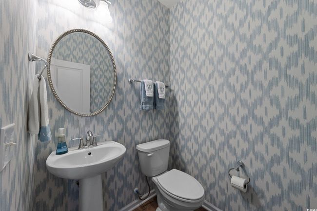 Half bathroom featuring toilet, wallpapered walls, baseboards, and wood finished floors | Image 13