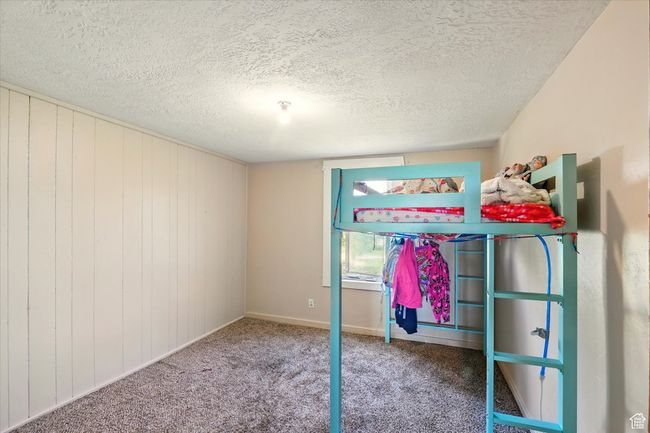 Unfurnished bedroom with a textured ceiling, carpet floors, and baseboards | Image 12