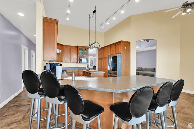 Kitchen featuring a breakfast bar, a center island, a ceiling fan, baseboards, and appliances with stainless steel finishes | Image 18