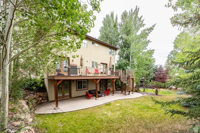 Rear view of property featuring a lawn, french doors, a patio, stucco siding, and stairs | Image 31