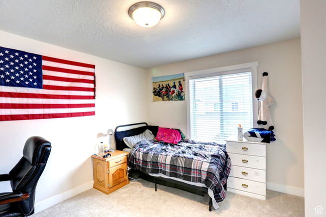 Bedroom featuring light colored carpet, a textured ceiling, and baseboards | Image 17