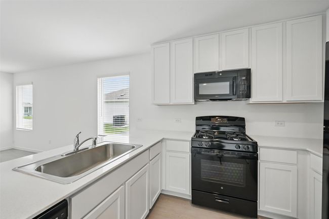 Kitchen featuring black appliances, healthy amount of natural light, and white cabinetry | Image 7