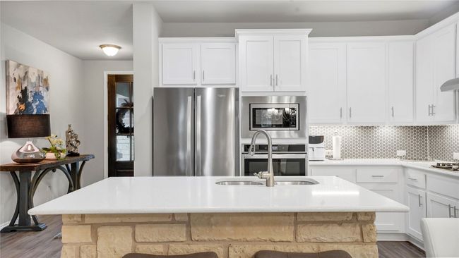 Kitchen with light countertops, white cabinetry, appliances with stainless steel finishes, and wood finished floors | Image 5