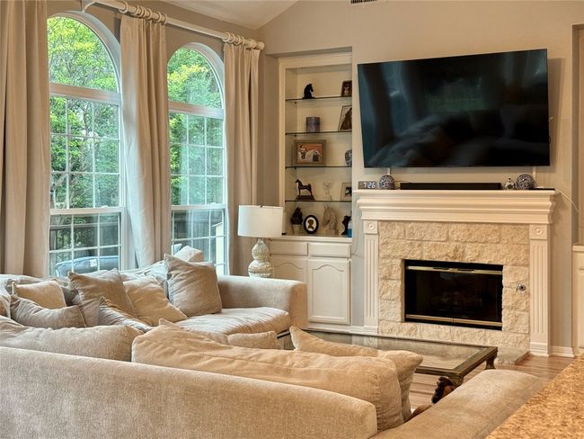 Living area featuring wood finished floors, a premium fireplace, built in shelves, and lofted ceiling | Image 14
