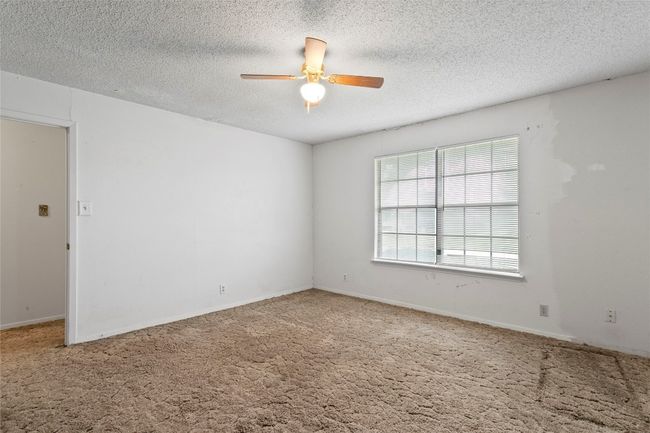 Carpeted empty room with ceiling fan and a textured ceiling | Image 25