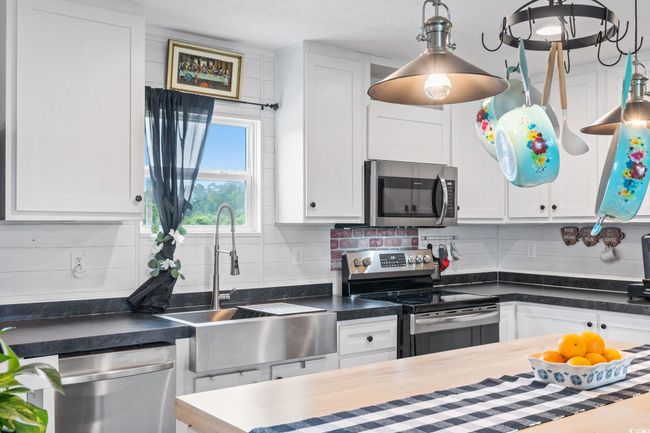 Kitchen with appliances with stainless steel finishes, a sink, white cabinetry, and tasteful backsplash | Image 13