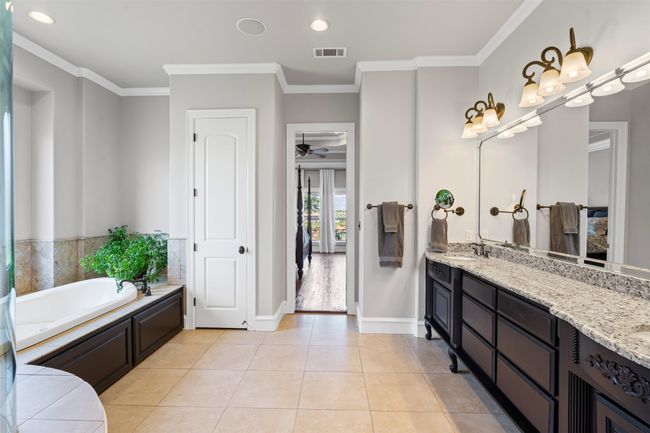 Bathroom featuring a garden tub, double vanity, visible vents, and crown molding | Image 20