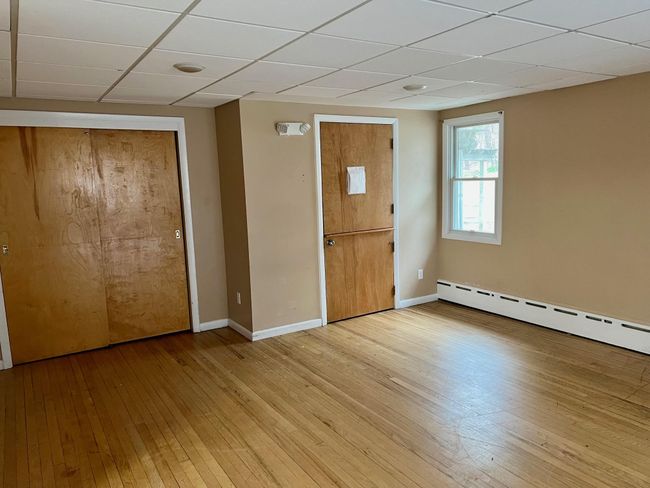 Empty room featuring a baseboard radiator, a paneled ceiling, light wood-type flooring, and baseboards | Image 15