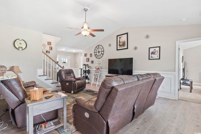 Living area with ceiling fan, light wood-type flooring, wainscoting, stairs, and vaulted ceiling | Image 8