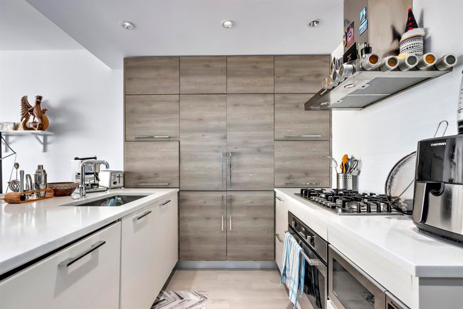 Kitchen featuring range hood, stainless steel appliances, a sink, light countertops, and modern cabinets | Image 9