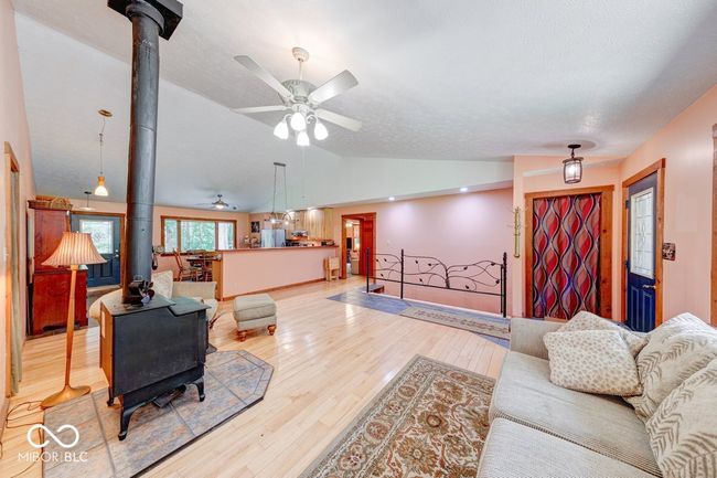 living area with a wood stove, ceiling fan, vaulted ceiling, and light wood finished floors | Image 48
