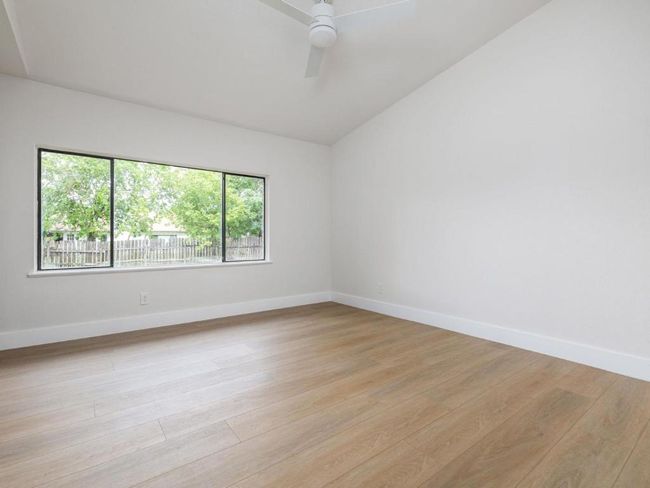 Spare room featuring light wood finished floors, lofted ceiling, and ceiling fan | Image 20