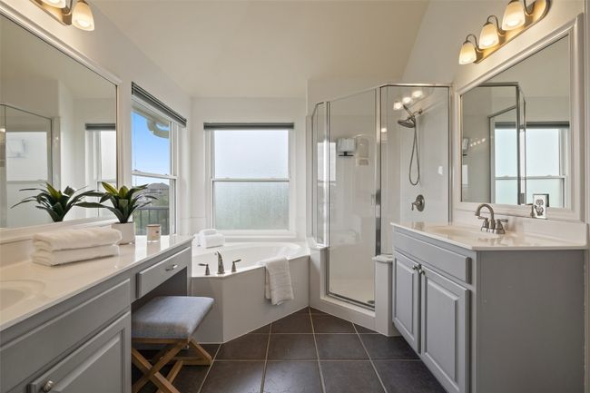 Bathroom with two sinks, vanity, a stall shower, a garden tub, and dark tile patterned floors | Image 27