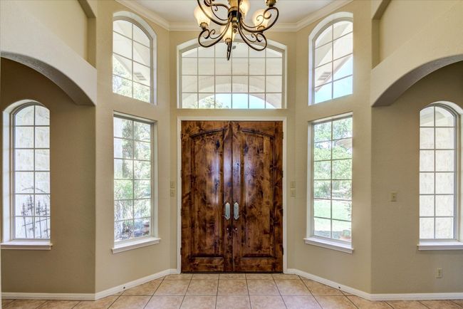 Foyer featuring stunning doors, soaring ceilings, crown molding, arched walkways, and an inviting chandelier | Image 4