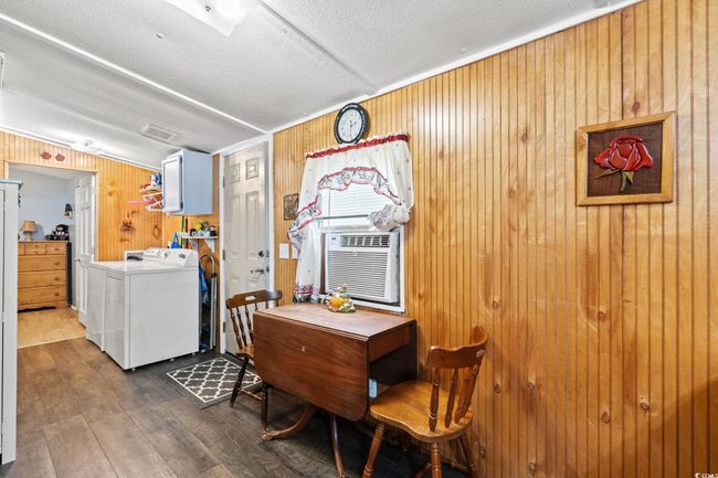 Dining space with wood finished floors, a textured ceiling, wooden walls, cooling unit, and washer and clothes dryer | Image 10