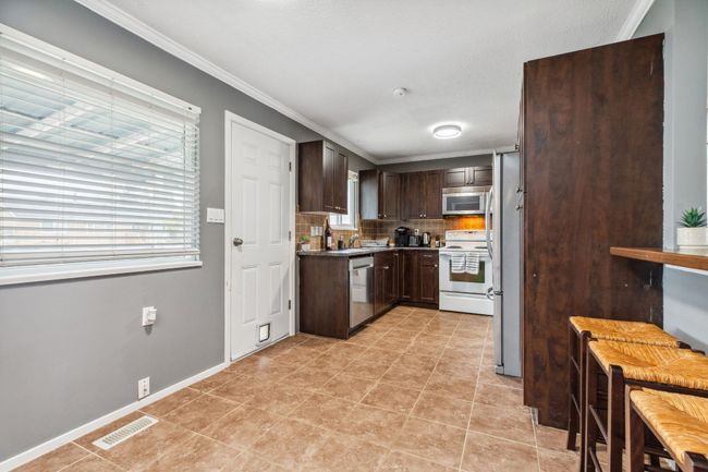Kitchen featuring visible vents, ornamental molding, appliances with stainless steel finishes, dark brown cabinets, and decorative backsplash | Image 15