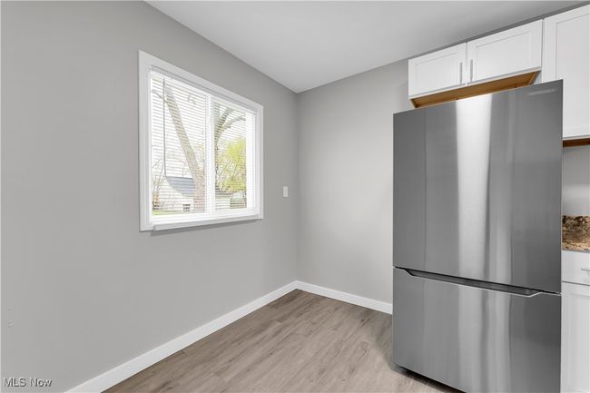Kitchen with light wood-type flooring, white cabinetry, baseboards, stone countertops, and freestanding refrigerator | Image 7