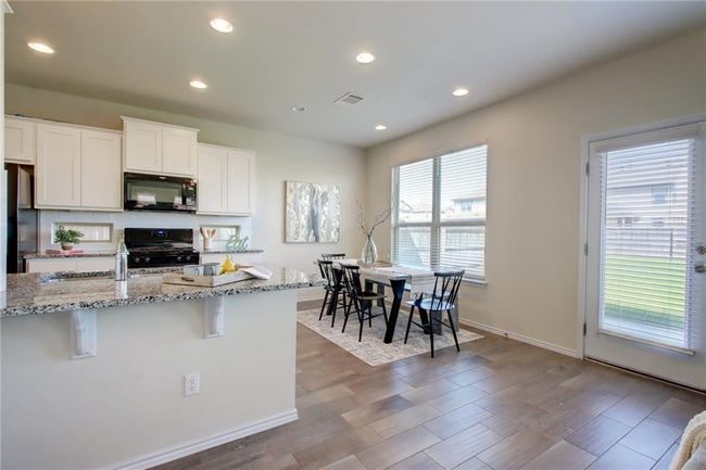 Kitchen featuring black appliances, light stone counters, white cabinets, recessed lighting, and wood finished floors | Image 7