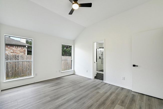 Empty room with a ceiling fan, wood finished floors, and vaulted ceiling | Image 18