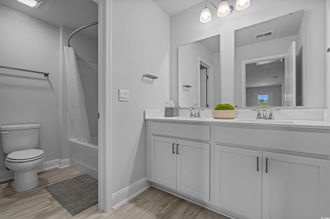 Full bath with double vanity, toilet, shower / bath combo, and wood finished floors | Image 33