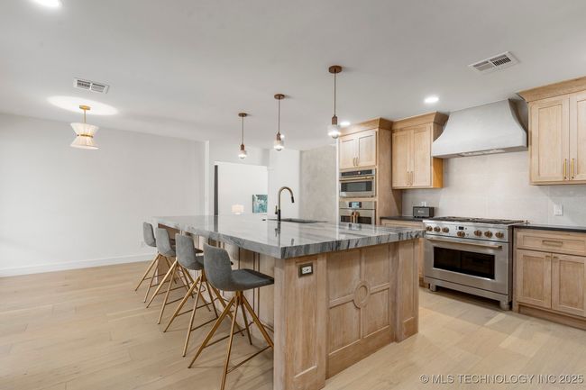 Main kitchen with luxury counters, luxury appliances, bar seating, and custom cabinets | Image 17