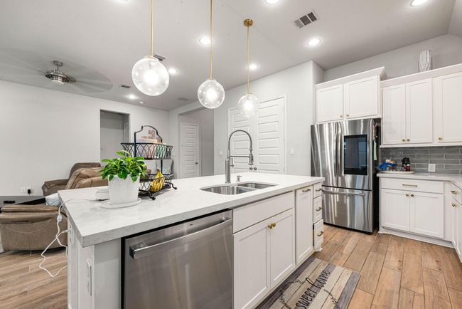 This kitchen is by far any chef’s dream! This spacious kitchen features large windows, white cabinets, quartz countertops, SS appliances, custom modern tile backsplash, recessed lighting with additional custom pendant lighting, quartz kitchen island with double sink and space for breakfast bar and a walk-in pantry all overlooking your huge family room. | Image 6
