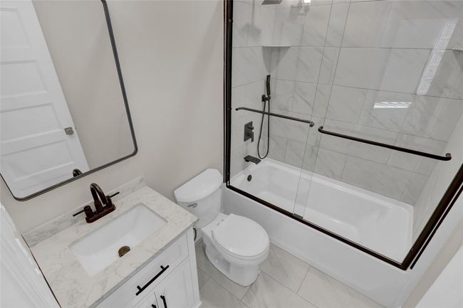 Full bath featuring toilet, marble finish floor, shower / bath combination with glass door, and vanity | Image 17